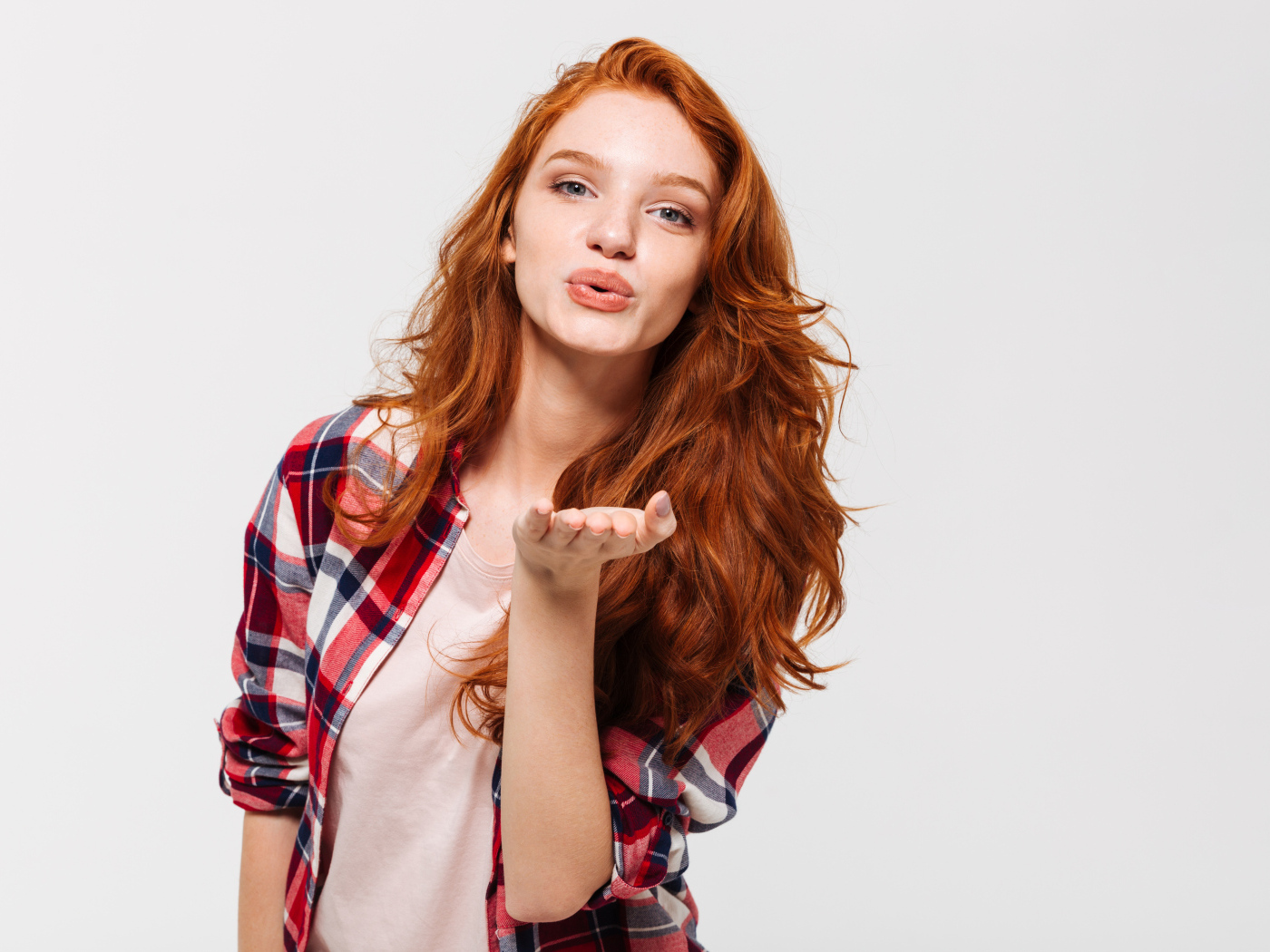 Красивая рыжеволосая девушка шлет воздушный поцелуй