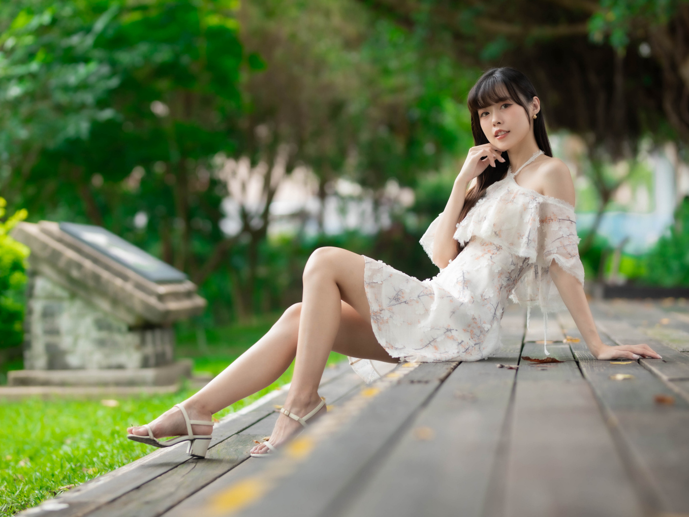 Симпатичная молодая азиатка сидит на деревянном покрытии