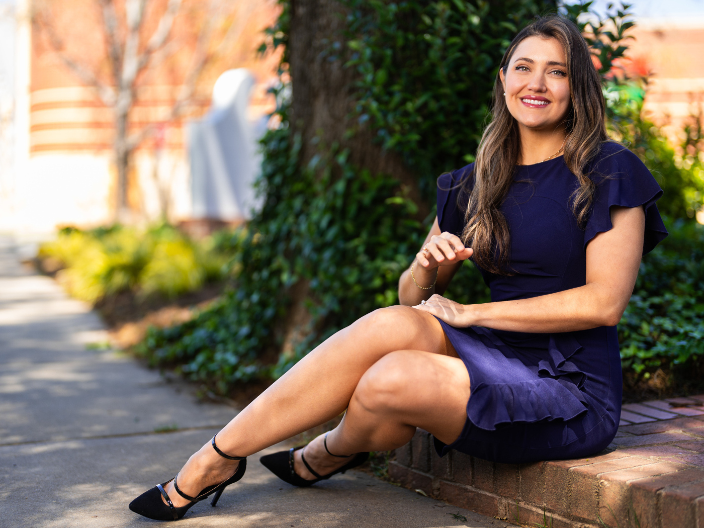 Улыбающаяся женщина в синем платье сидит на земле