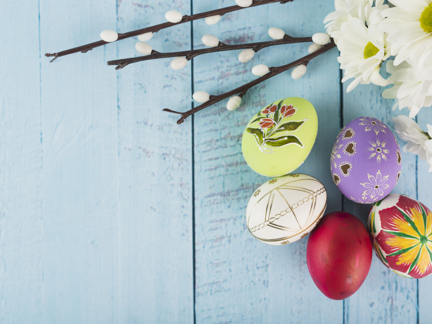 Красивые пасхальные яйца с ветками вербы и цветами хризантемы на голубом фоне