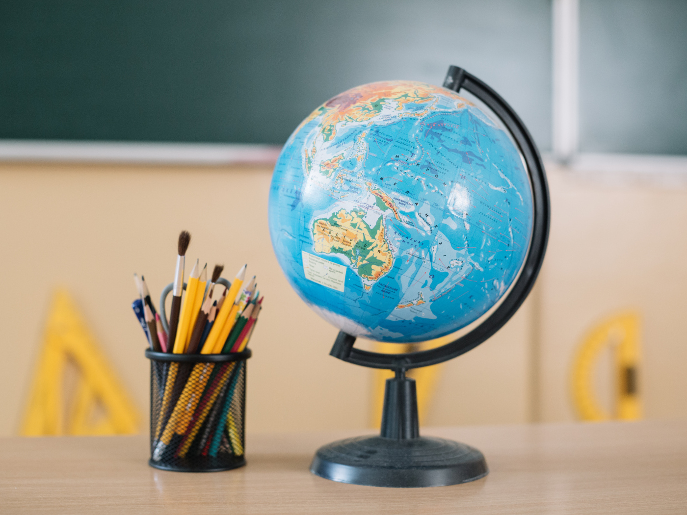 Глобус на столе с карандашами в школе