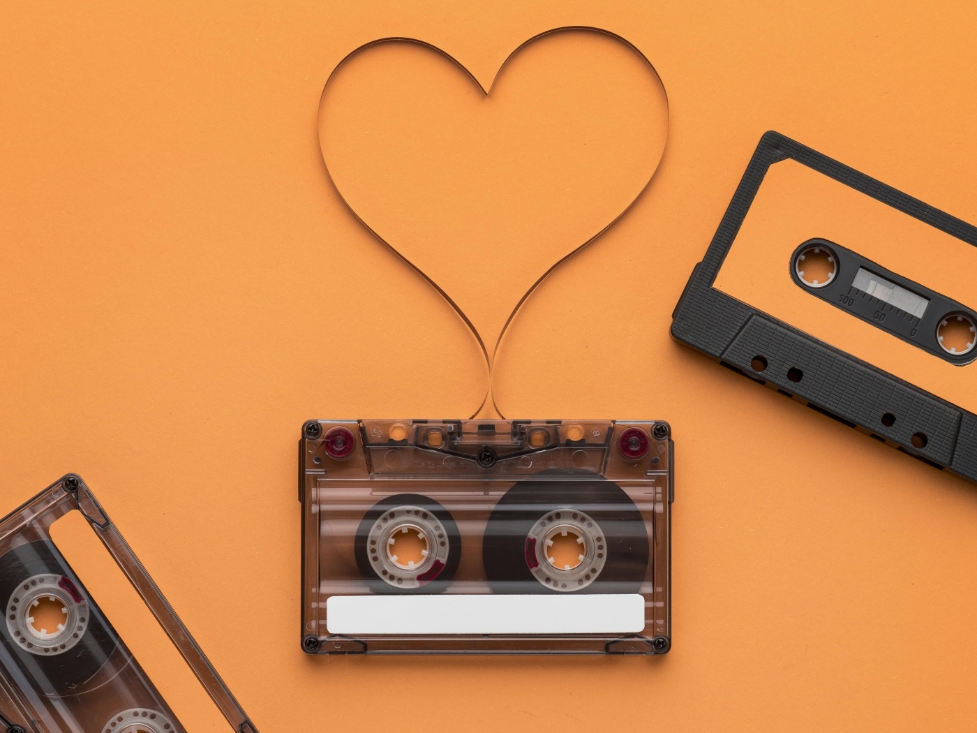 Кассеты и сердце из ленты на оранжевом фоне