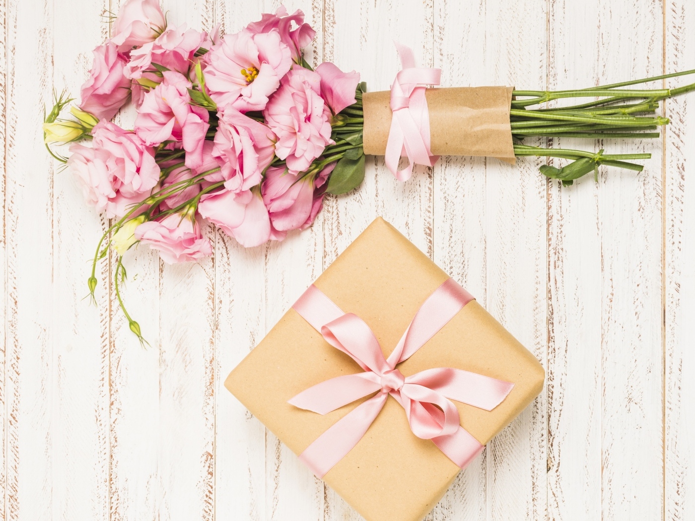 Букет розовых цветов эустомы с подарком на деревянном фоне