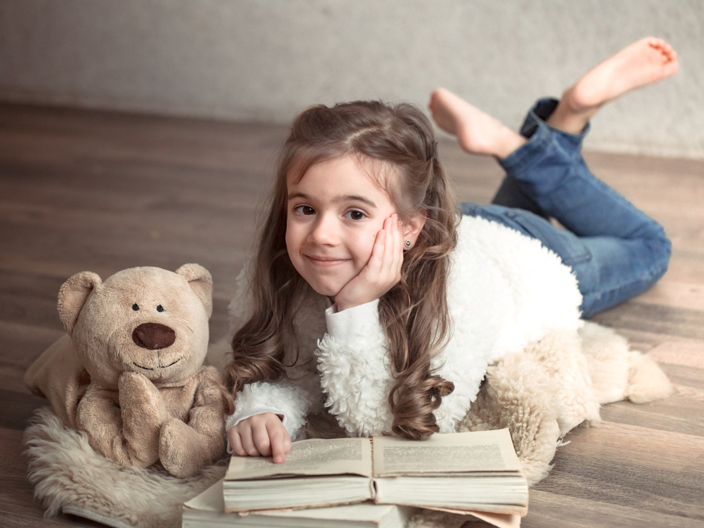 Девочка с медведем и книгой лежит на полу