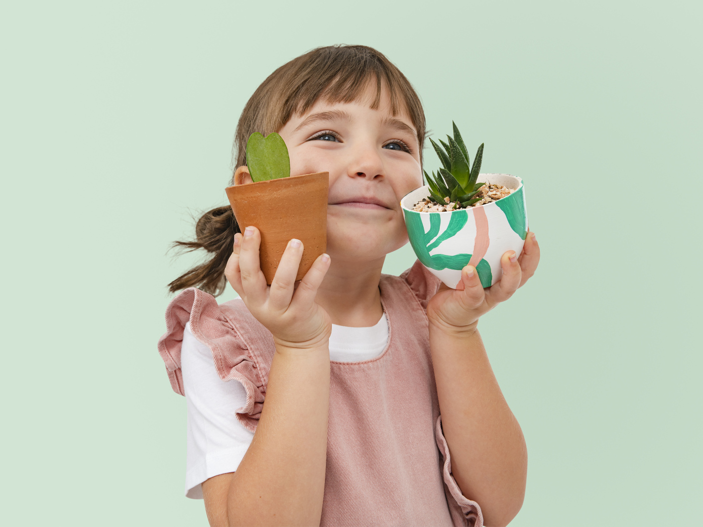 Маленькая девочка с комнатными цветами в руках