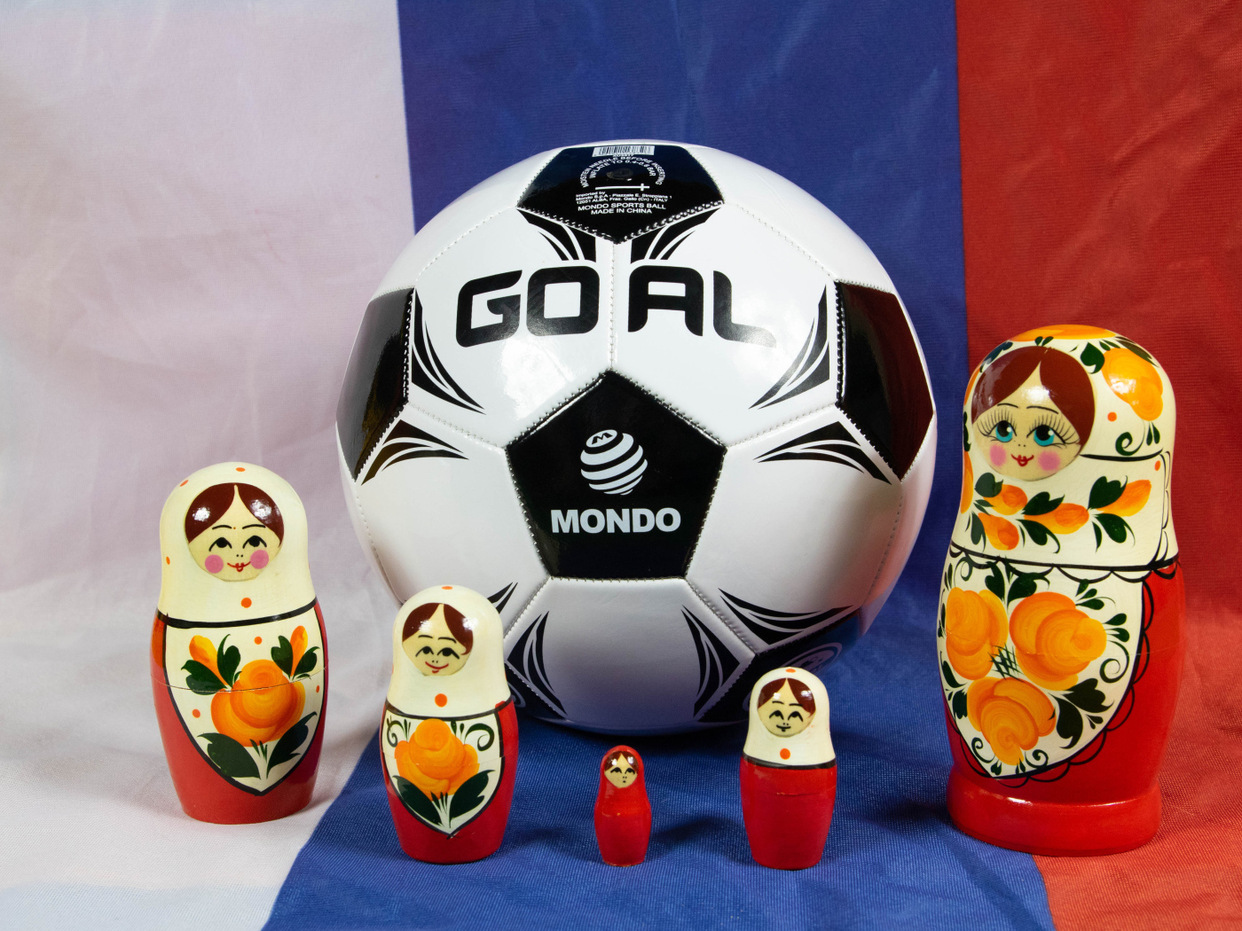 Матрешки и футбольный мяч на фоне флага России
