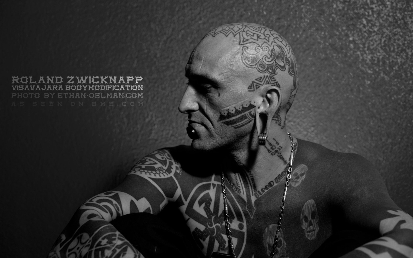 Мужчина с пирсингом в губе и татуировками