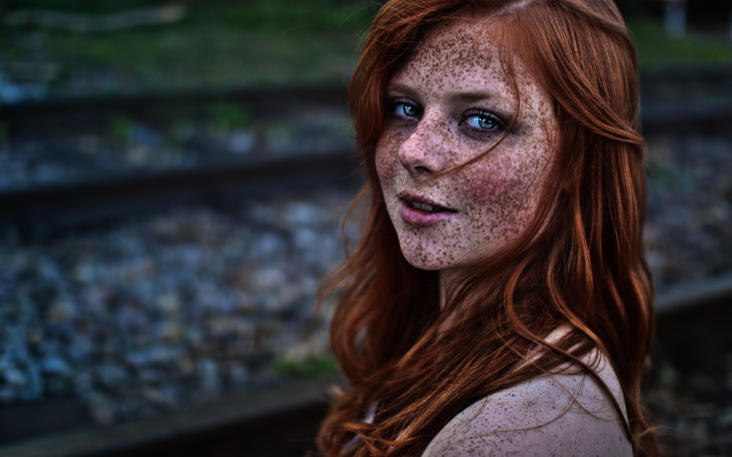 Девушка с веснушками на фоне рельс