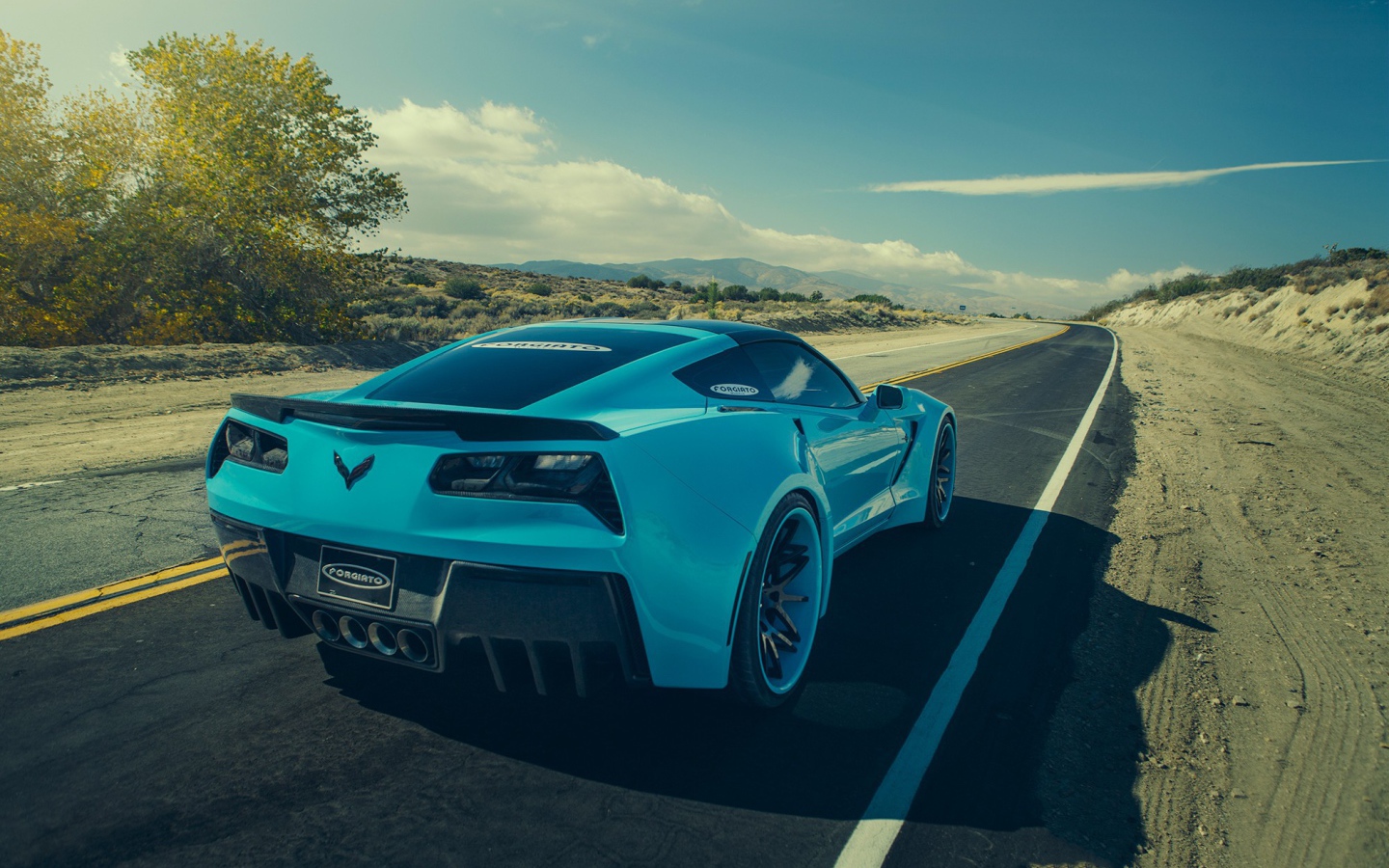 Голубой спортивный Chevrolet на шоссе в жаркой пустыне