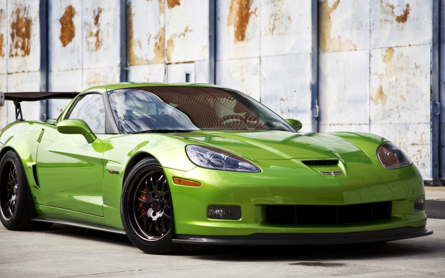 Зеленый Chevrolet Corvette на фоне стены