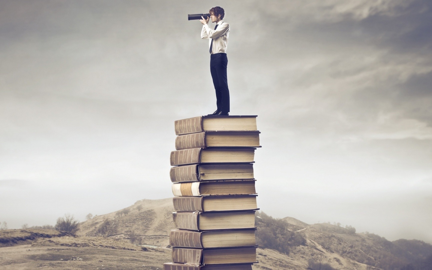 Мужчина с подзорной трубой на стопке книг