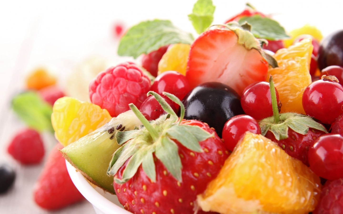 Кусочки спелых фруктов и ягоды на тарелке