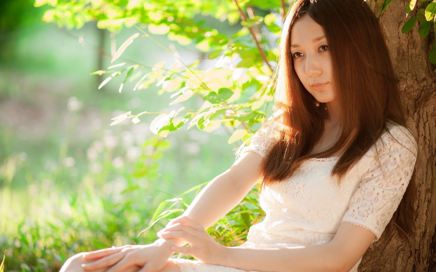 Азиатская девушка прислонилась спиной к дереву