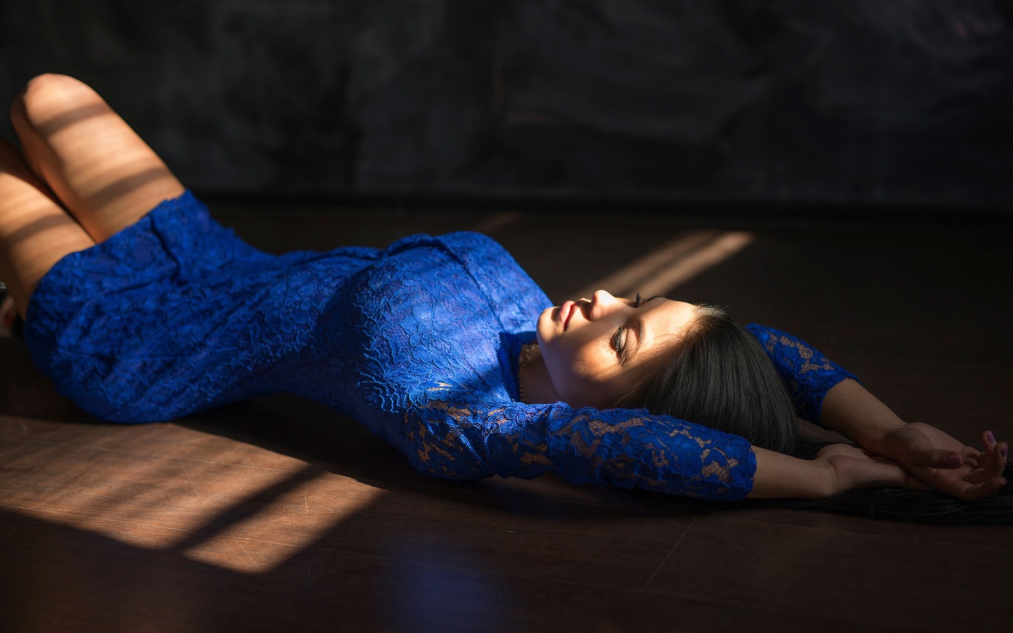 Девушка в голубом кружевном платье лежит на полу