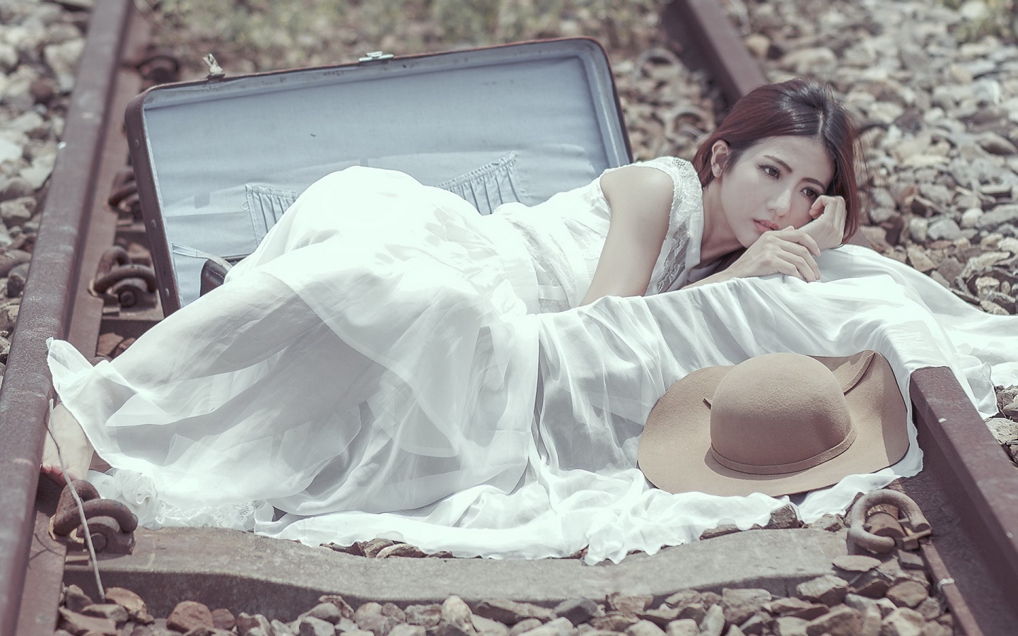 Девушка лежит в чемодане на рельсах