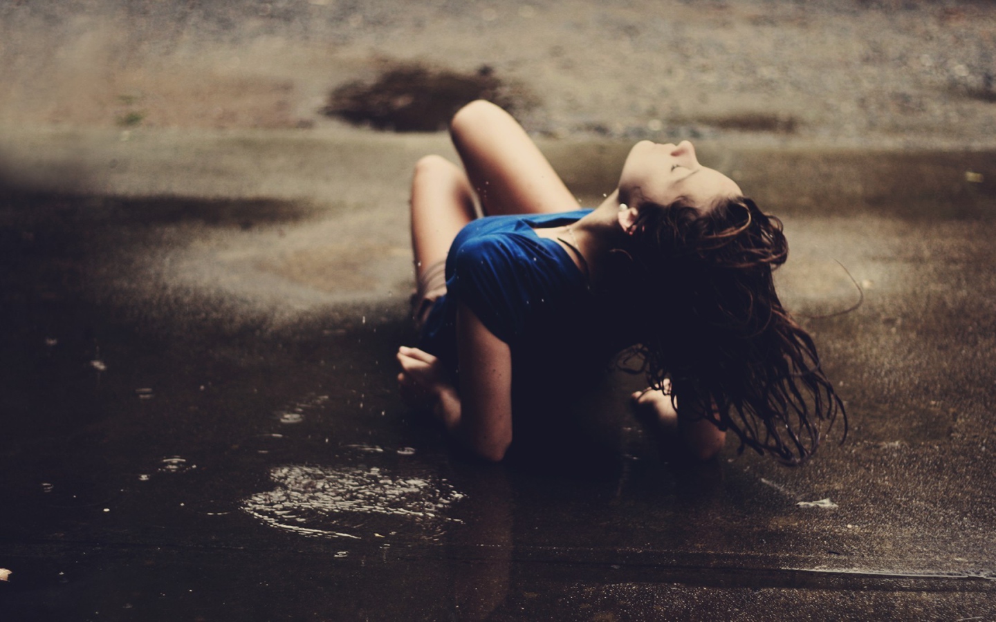 Девушка лежит на асфальте под дождем