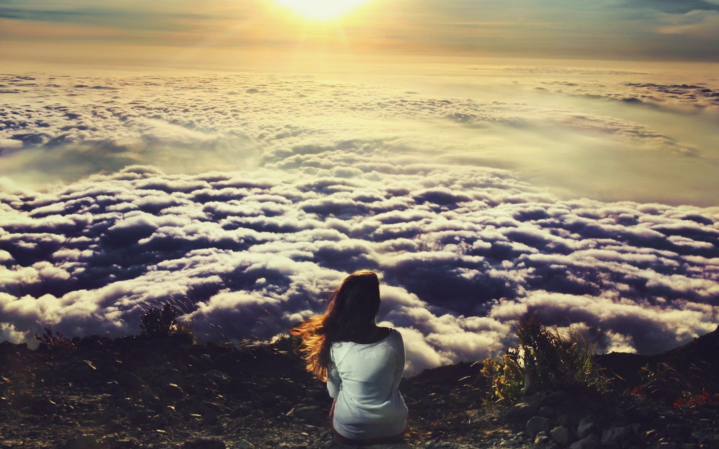 Девушка сидит и смотрит на облака