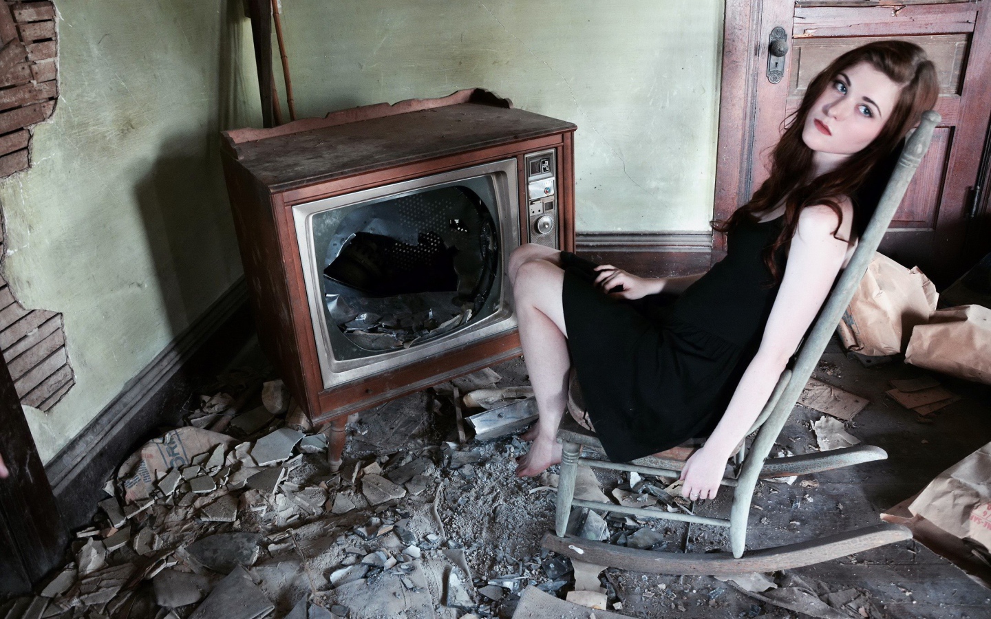 Девушка сидит у разбитого старого телевизора