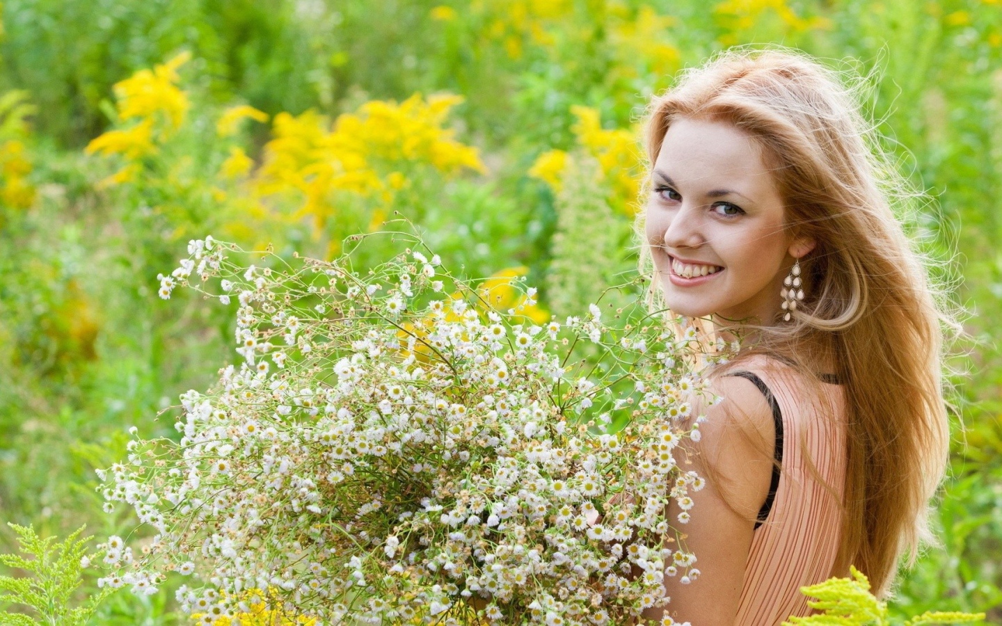 Девушка улыбается, держа в руках букет ромашек