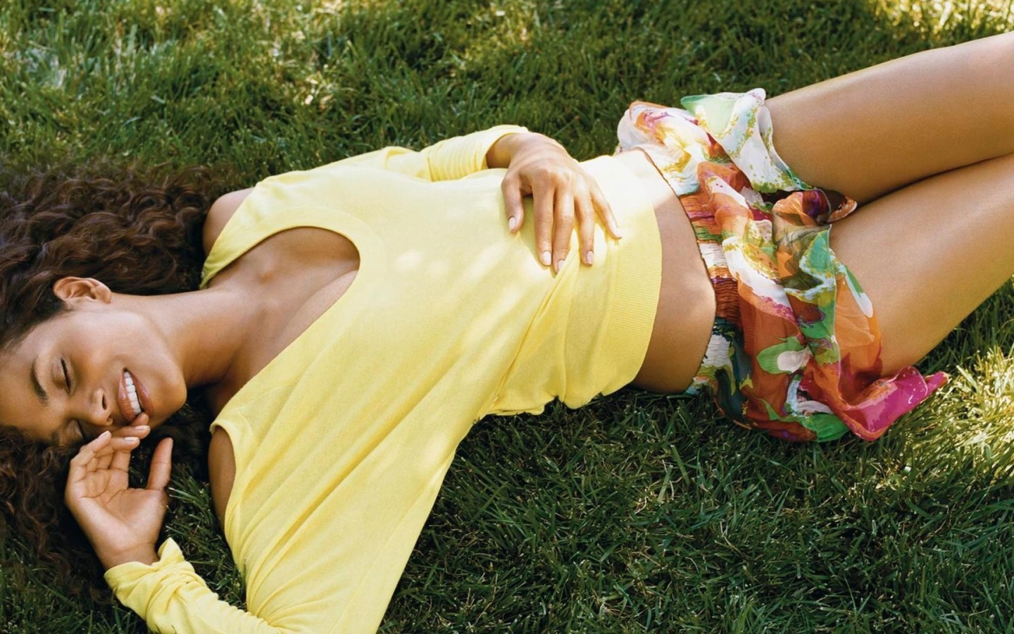 Мулатка в желтой футболке лежит на траве