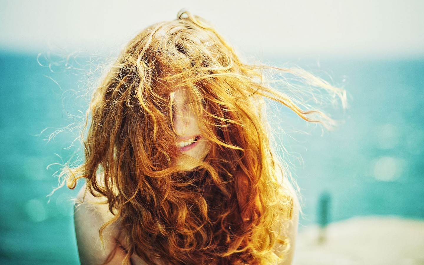 Ветер растрепал рыжие волосы у девушки