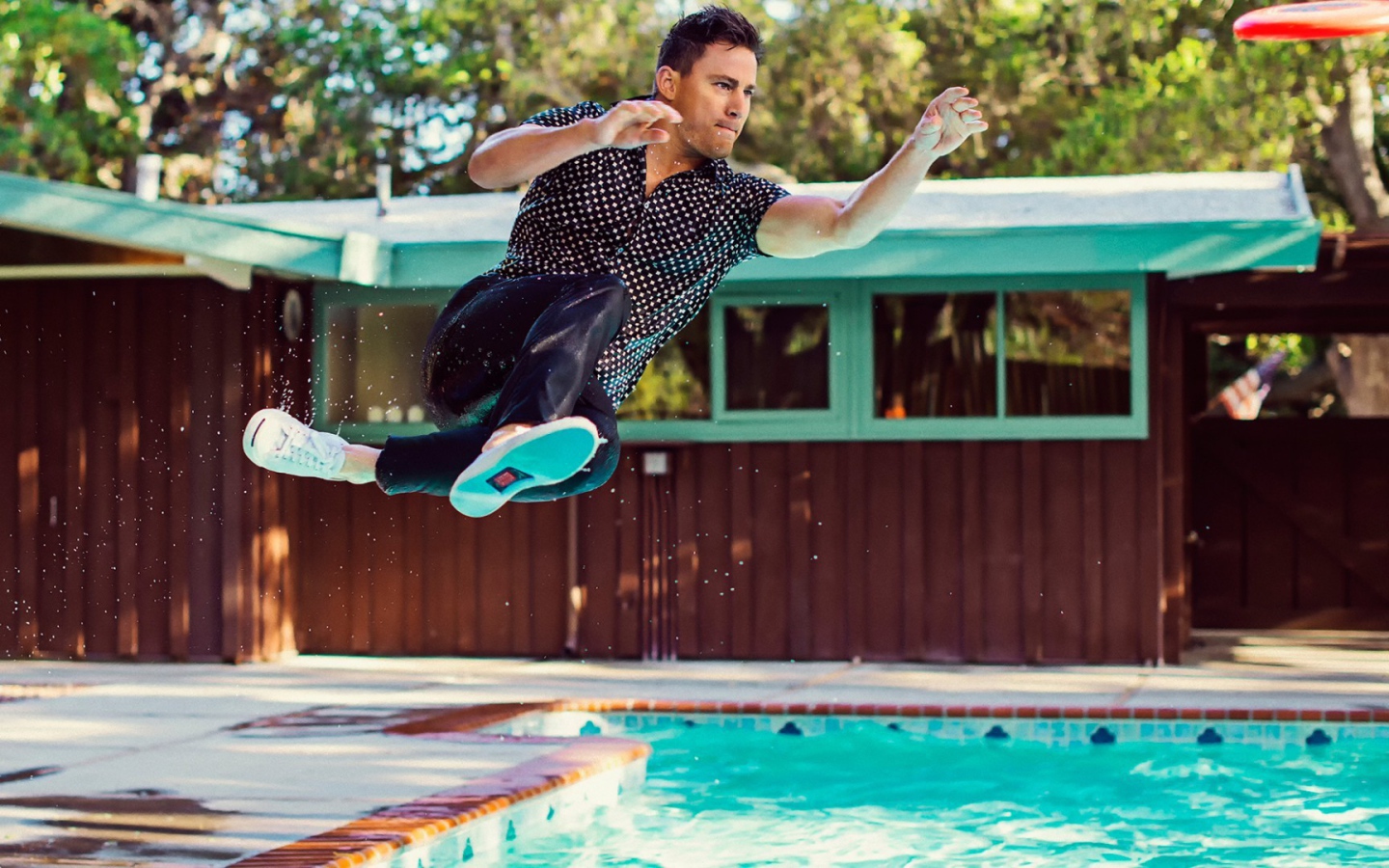Мужчина прыгает в бассейн в одежде