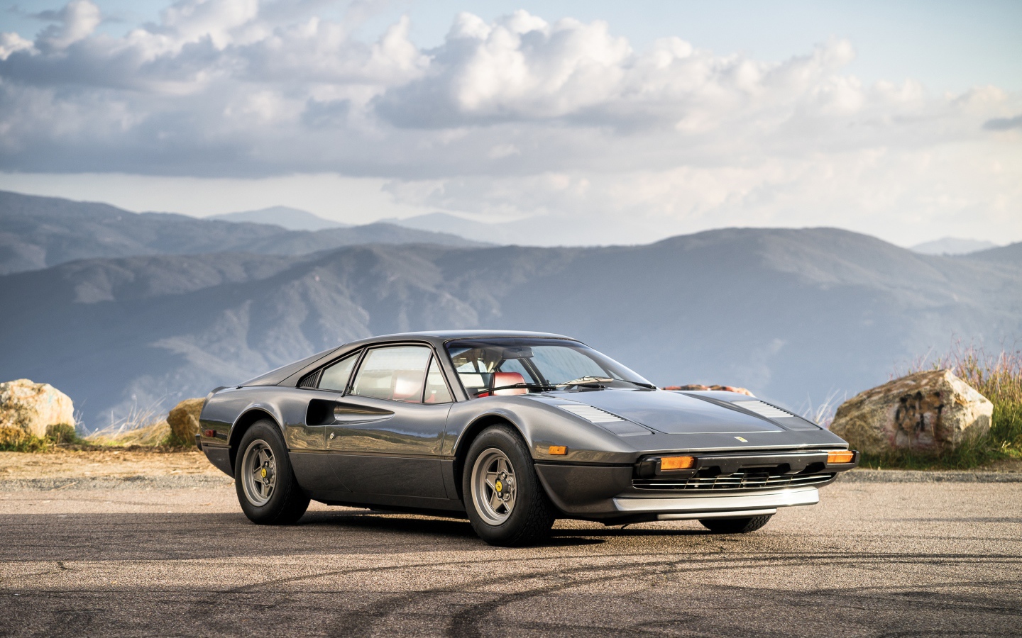 Суперкар Ferrari 308 gts серого цвета,   на фоне гор 