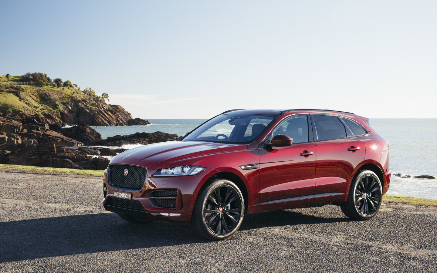 Бордовый автомобиль Jaguar F-Pace на фоне океана