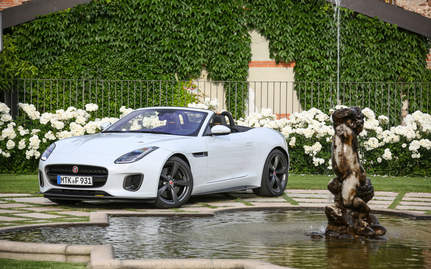 Белый автомобиль кабриолет Jaguar F-Type у фонтана