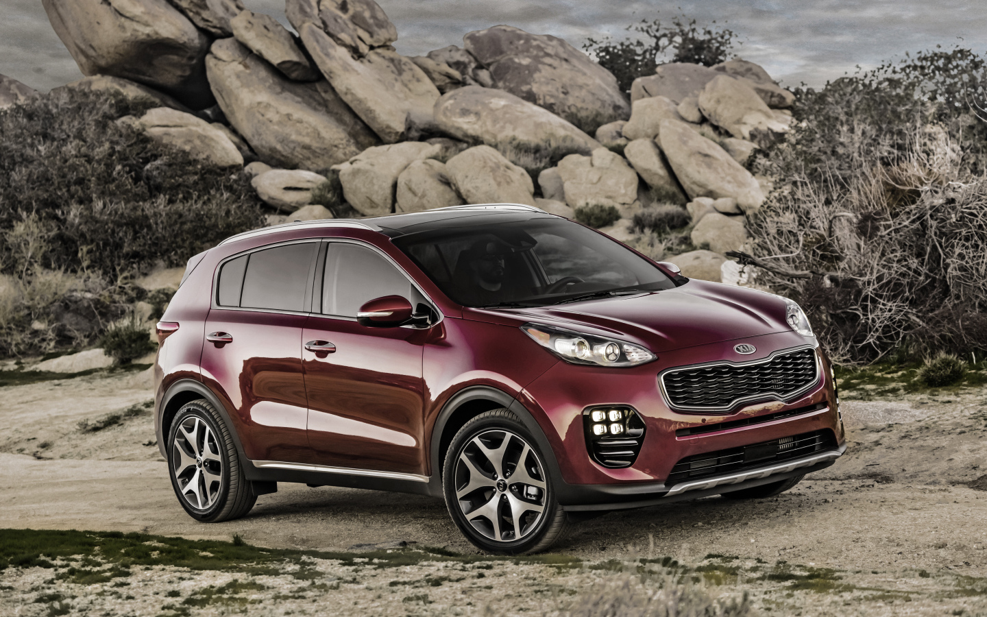 Стильный бордовый внедорожник Kia Sportage на фоне больших камней