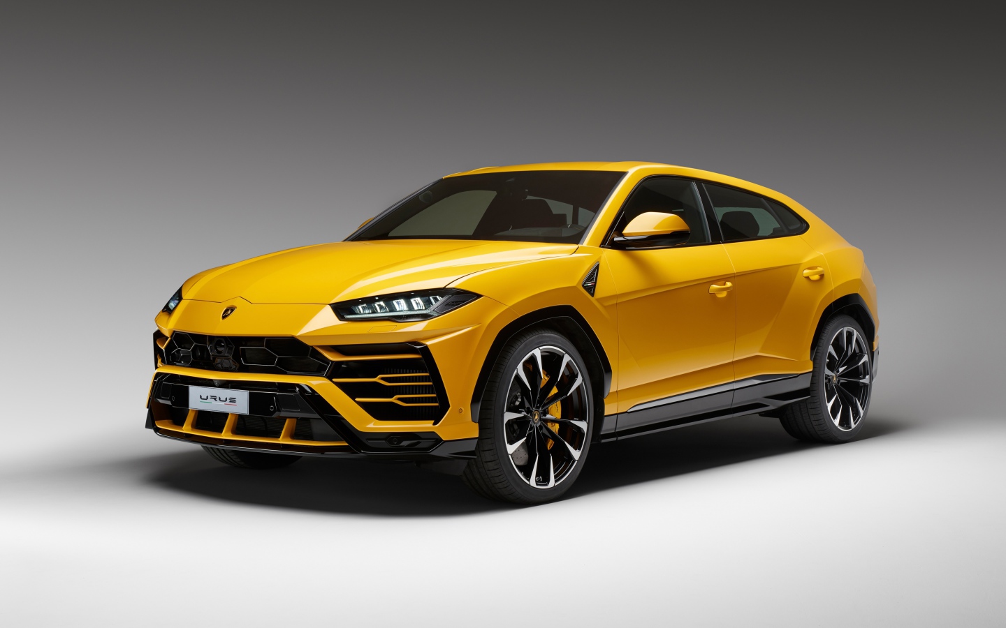 Желтый спортивный автомобиль Lamborghini Urus, 2018 на сером фоне