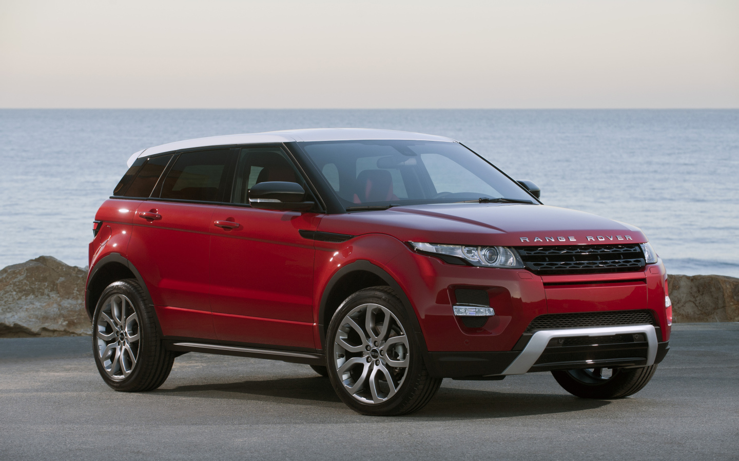 Красный автомобиль Land Rover Caractere на фоне океана