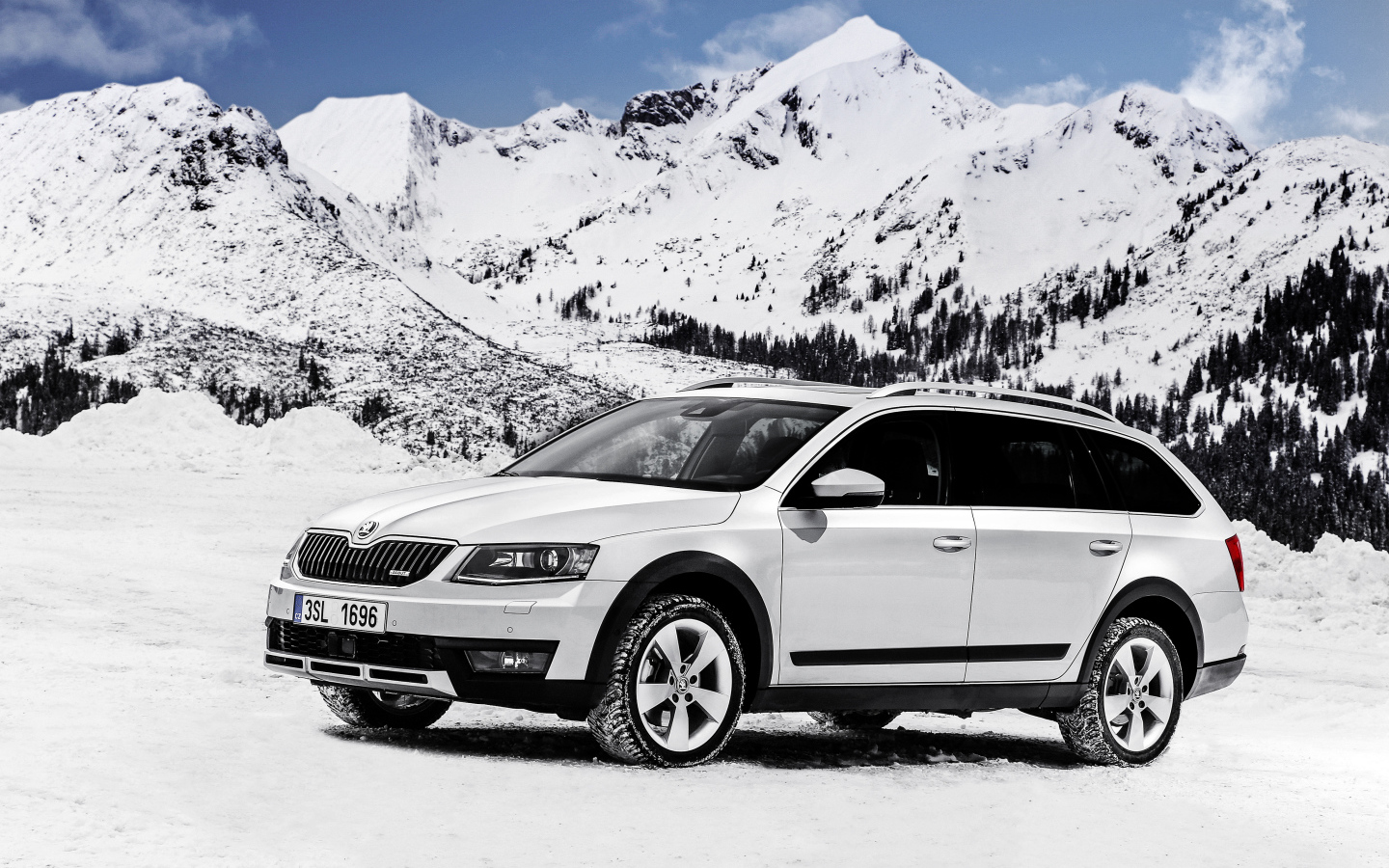 Белый автомобиль Skoda Octavia на фоне заснеженных гор