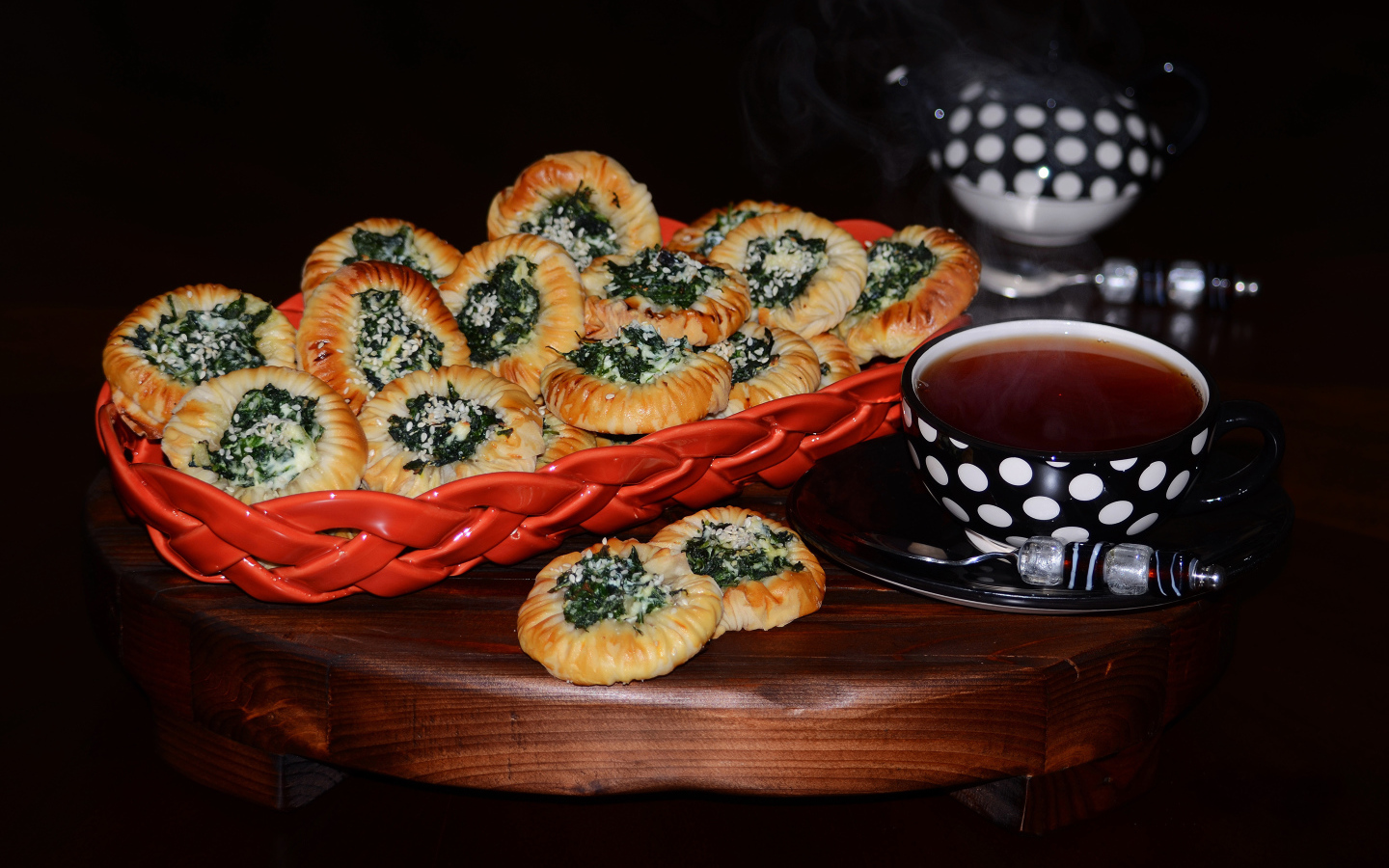 Булочки с зеленью и горячим чаем на черном фоне