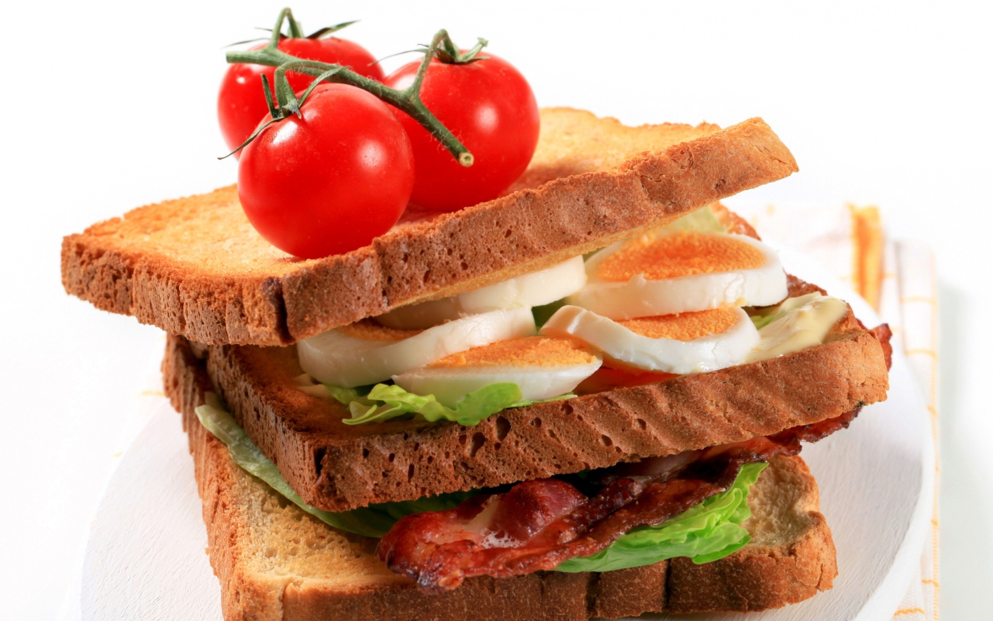 Сэндвич с беконом, яйцами и овощами на белом фоне