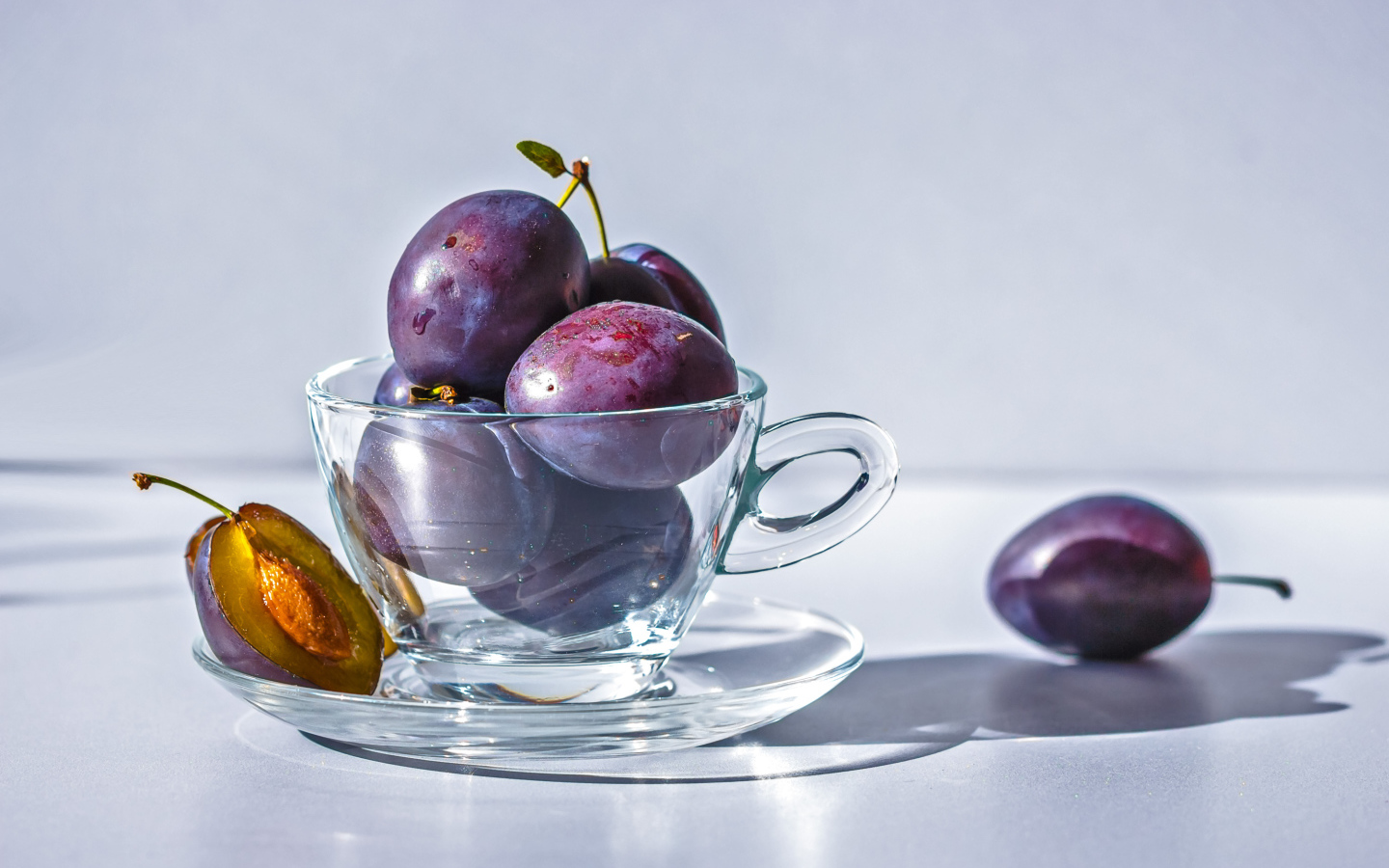 Спелые синие сливы на столе в стеклянной чашке