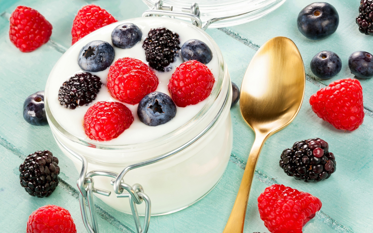 Йогурт со свежими ягодами малины, черники и ежевики в стеклянной банке на завтрак