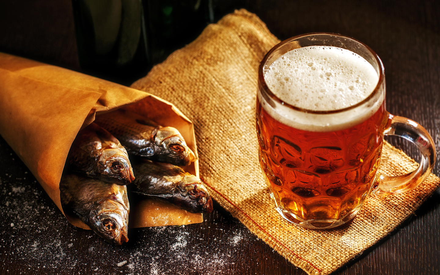 Бокал пива с сушеной рыбой на столе