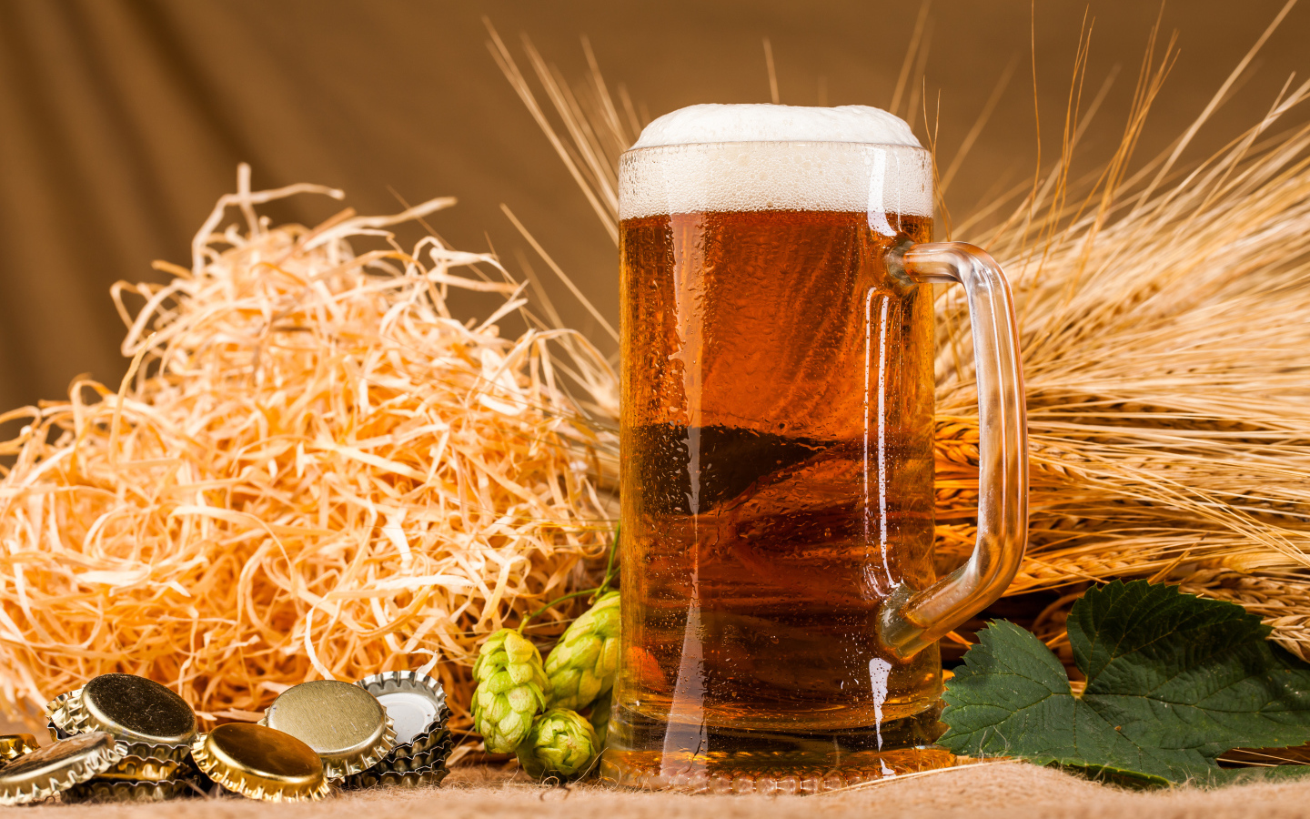 Бокал пива с пеной на столе с хмелем и соломой
