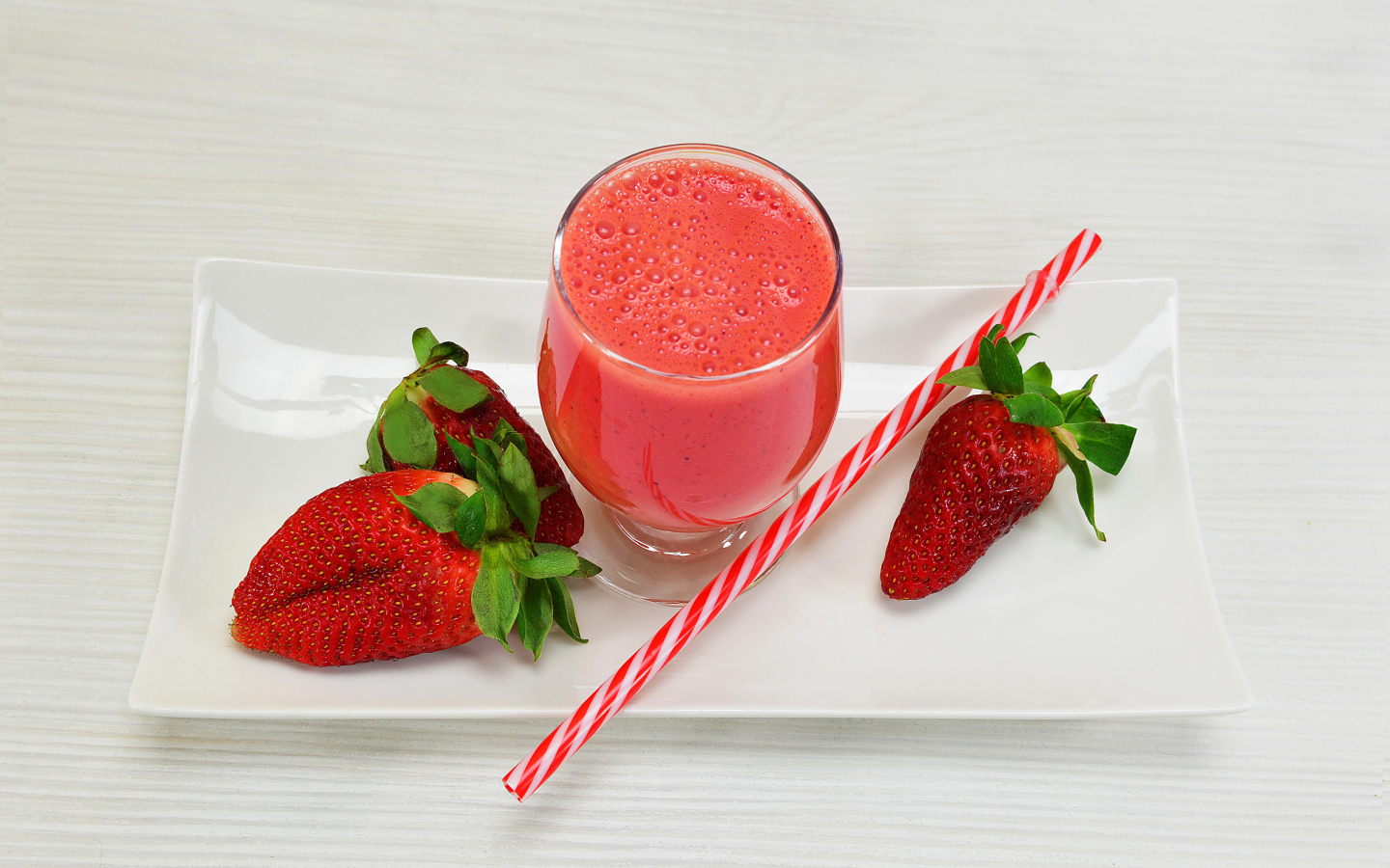 Бокал клубничного коктейля со свежей клубникой и трубочкой