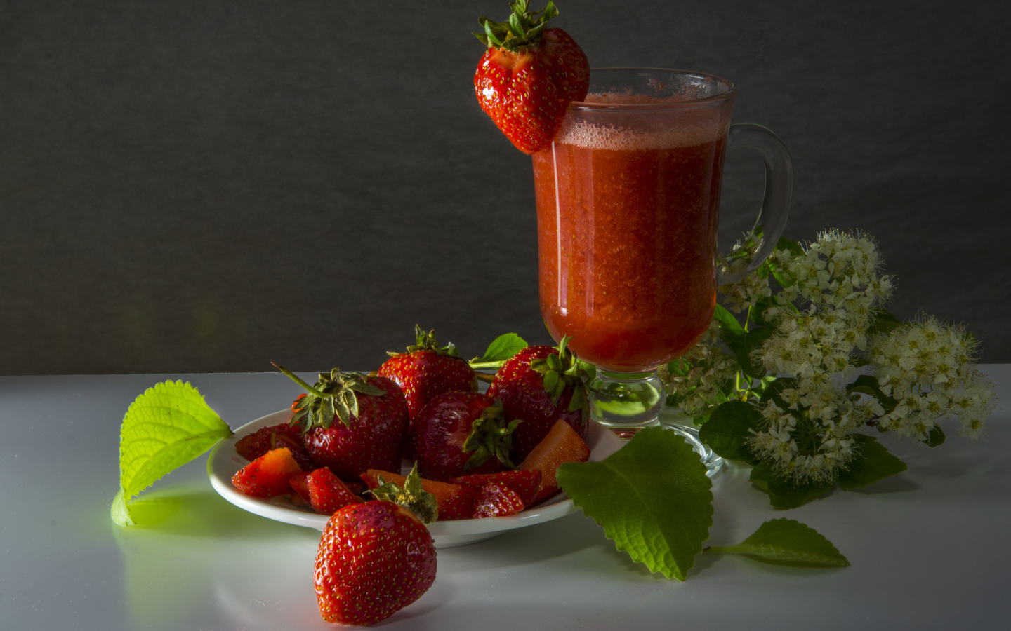 Стакан клубничного сока и свежая клубника на столе