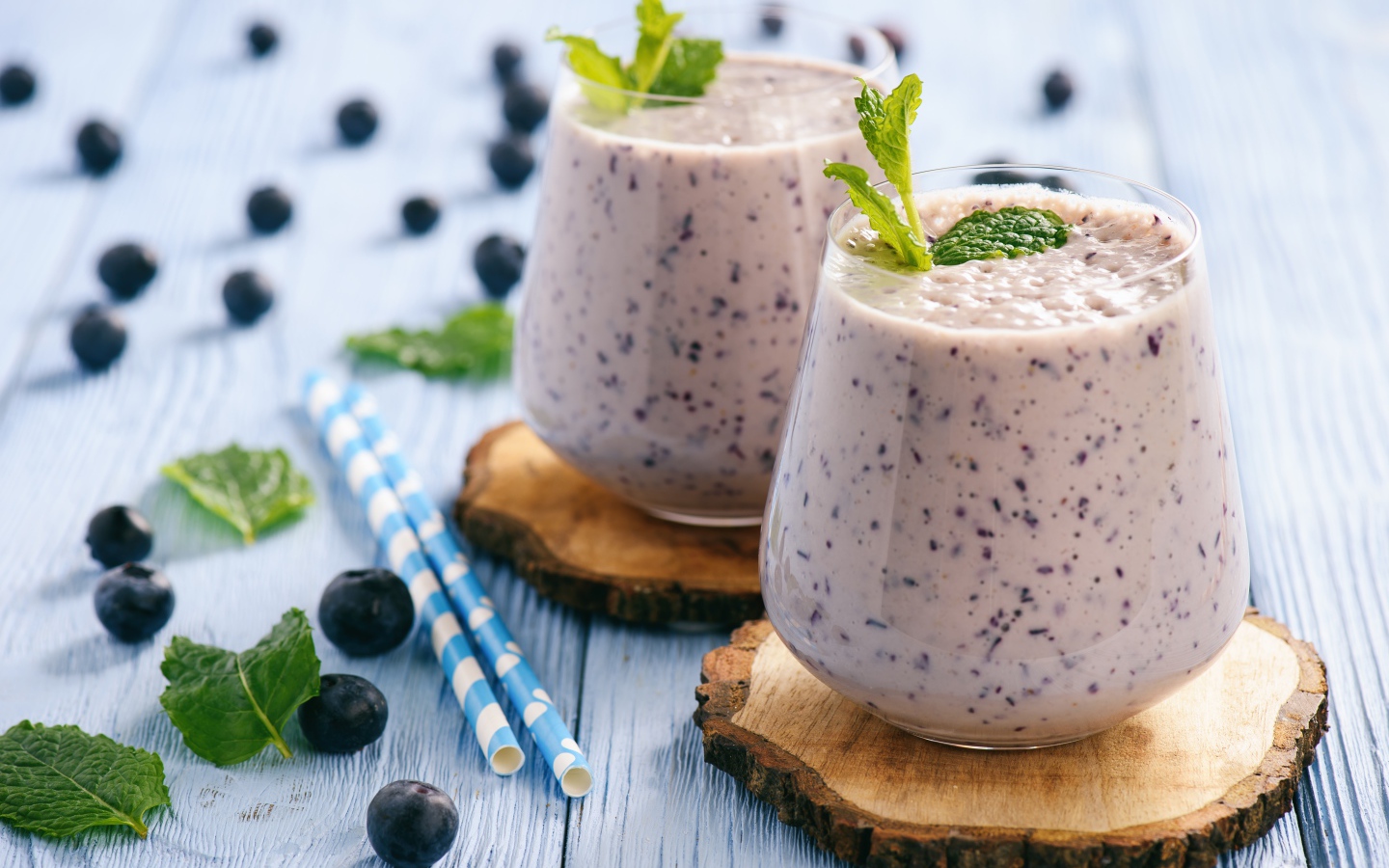 Черничный смузи на столе со свежими ягодами и трубочками