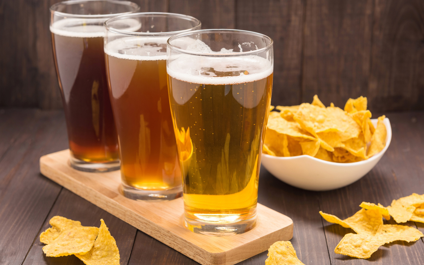 Три стакана пива на столе с чипсами