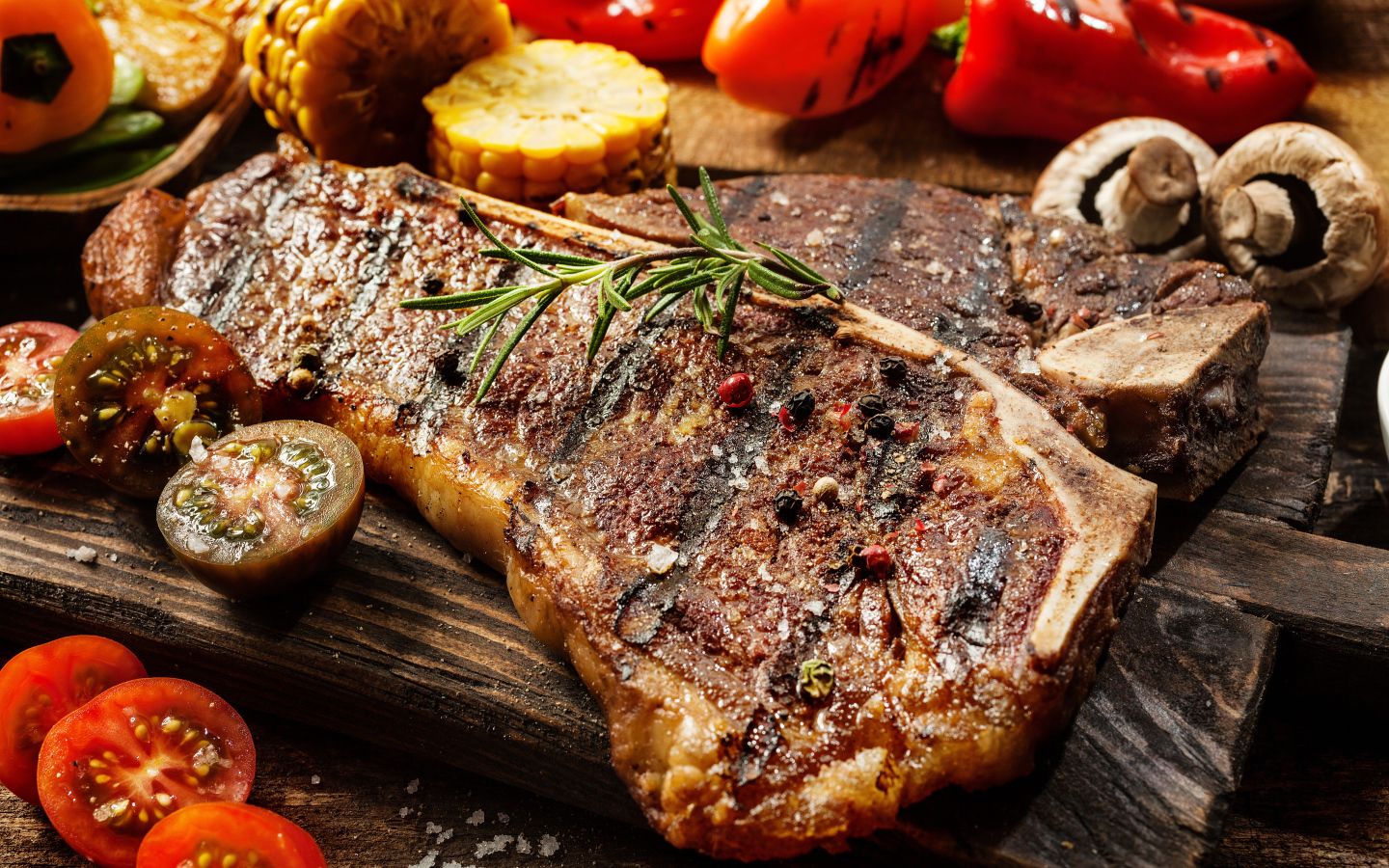 Кусок сочного жареного мяса на разделочной доске с овощами