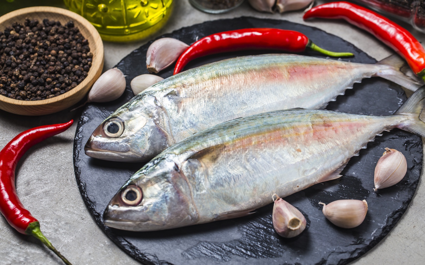 Свежая рыба на столе с красным перцем, чесноком и специями