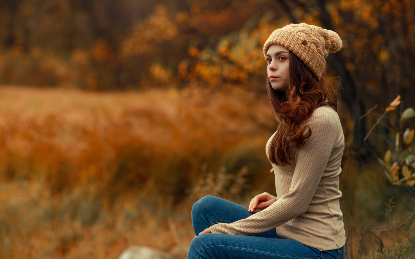 Молодая девушка в синих джинсах и теплой шапке