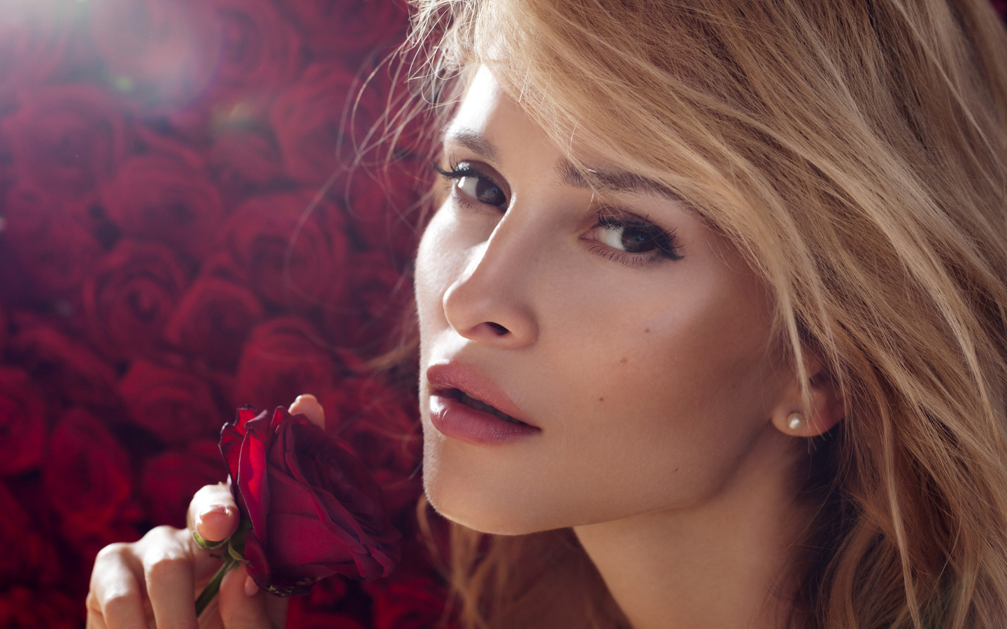 Красивая девушка блондинка с красной розой в руке