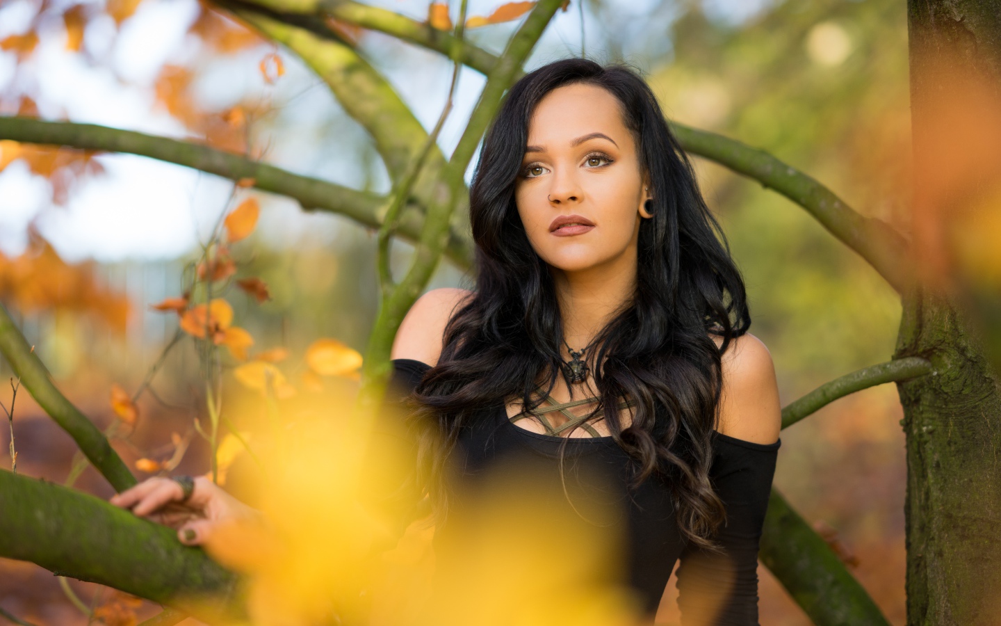 Красивая брюнетка у дерева в черном платье