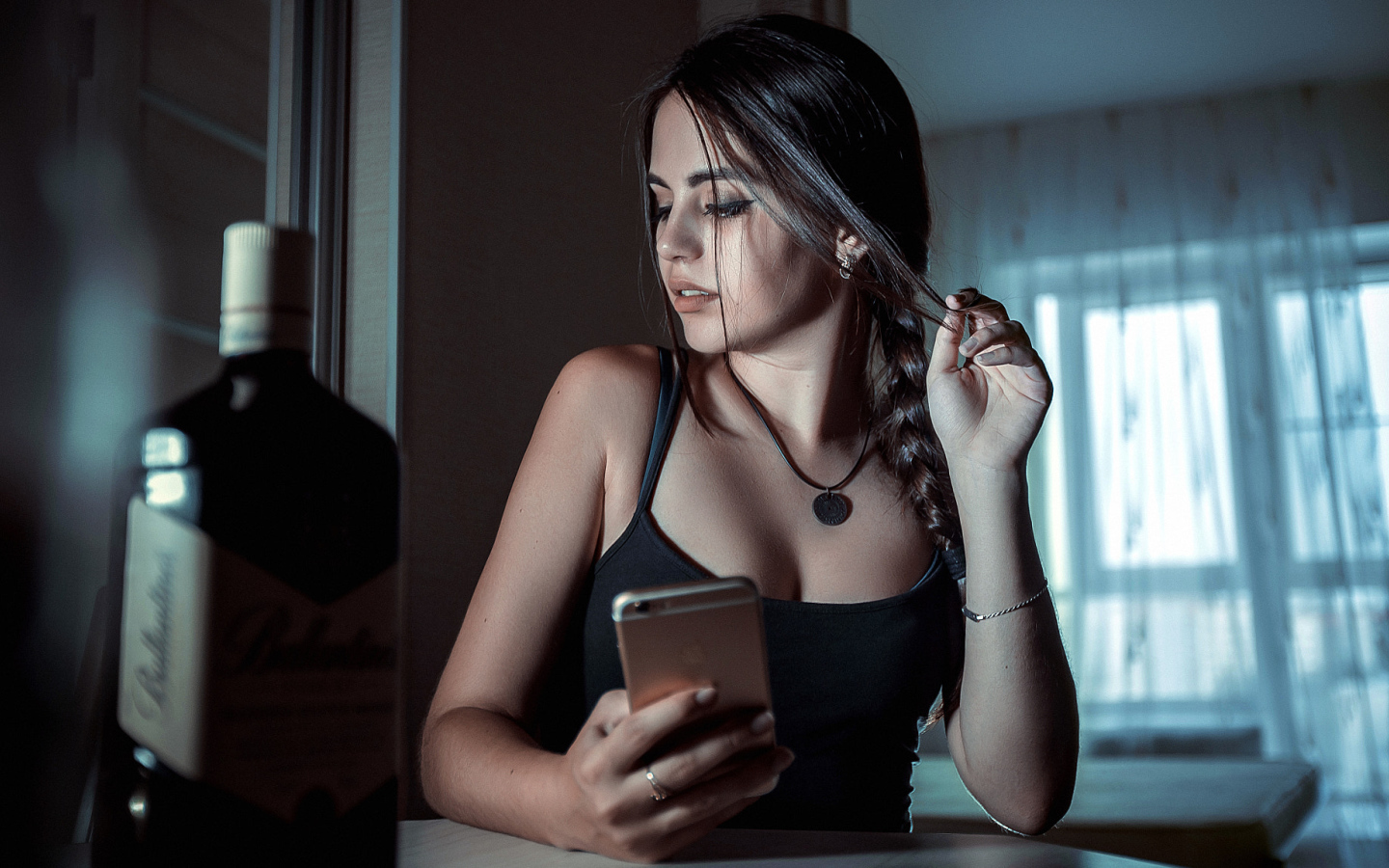 Красивая брюнетка с телефоном в руках и бутылкой