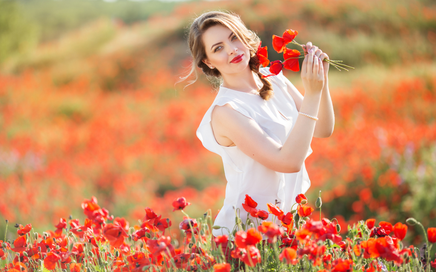Красивая девушка в белом платье с букетом маков в руках